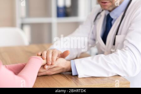 Porträt des reifen Arztes, der die Hände des weiblichen Patienten hält Stockfoto