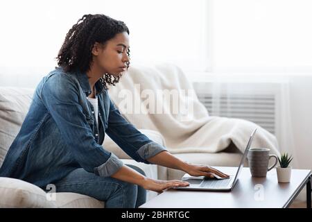 Junge African American Girl Desinfektion Laptop-Tastatur Vor Der Arbeit Zu Hause Stockfoto