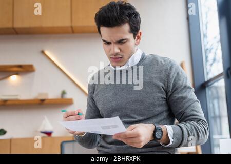 Besorgte Geschäftsmann mit Bleistift Blick auf Papier im Büro Stockfoto