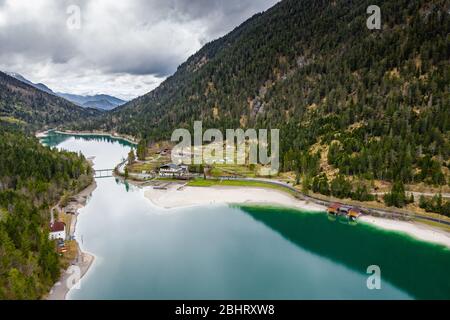 Die unwahrscheinliche Luftlandschaft des Sees, Italien, Drohne fliegt tief über azurblauem Wasser des Sees, einen leeren Strand, wolkig Wetter, Küste, Brücke Stockfoto