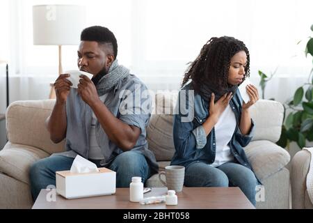 Familie, Die Zu Hause An Coronavirus Leidet. Krank Schwarz Paar Husten Auf Couch Stockfoto