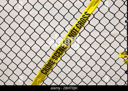 Gelbes Crime Tape, das an einem schwarzen Liink-Zaun gehängt wird Stockfoto