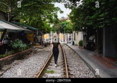 Frau, die auf den Gleisen der Eisenbahn in einer städtischen Umgebung läuft Stockfoto
