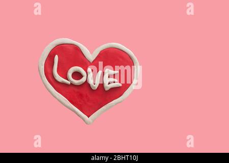 Rotes Herz mit dem Wort Liebe aus Plastilin auf einem rosa Hintergrund isoliert Stockfoto