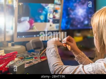 Online Fernstudium zu Hause während der Quarantäne. Ein kleines Mädchen sammelt einen mehrfarbigen Konstruktor an einem Tisch Stockfoto