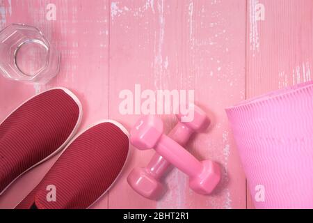 Nahaufnahme der rosa Farbe Hantel und Glas Wasser auf dem Tisch Stockfoto