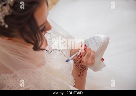 Braut schreibt unter Schuh Hochzeit Ritual Aberglauben. Hand einer Braut schriftlich Single Freunde Namen unter ihrem Schuh vor der Hochzeit. Braut schreibt ihr Stockfoto