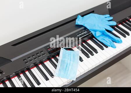 Auf dem Klavier liegen Virenschutzmaske und Handschuhe Stockfoto