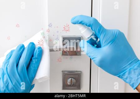 Hände in Schutzhandschuhe - einer hält die Spritze mit einem Antiseptikum, der andere - wischen den Türgriff mit einem Tuch angefeuchtet mit einem Desinfektionsmittel Stockfoto