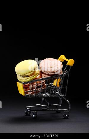 Makronen in Metall Warenkorb. Studio-Foto. Makronen auf dunklem Hintergrund, bunte französische Kekse Makronen. Makronen. Süßwarenfotografie Stockfoto