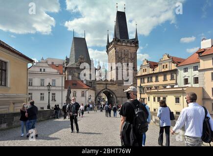 Prag, Tschechische Republik, 26. April 2020. Touristen mit Schutzmaske gehen nach dem Ausbruch der Kronenvirus-Pandemie im Frühjahr auf der mittelalterlichen Karlsbrücke Stockfoto