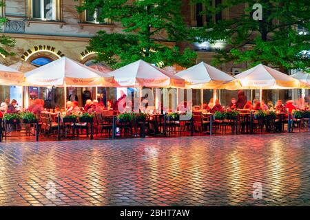 Regnerischer Abend mit Menschen auf Terrassen Marktplatz Krakau sitzen Stockfoto