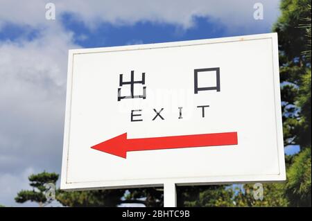 Schild mit einem roten Pfeil nach links und das Wort EXIT in englischer Sprache und in japanischen Kanji-Schrift die Symbole für beenden und Mund Stockfoto