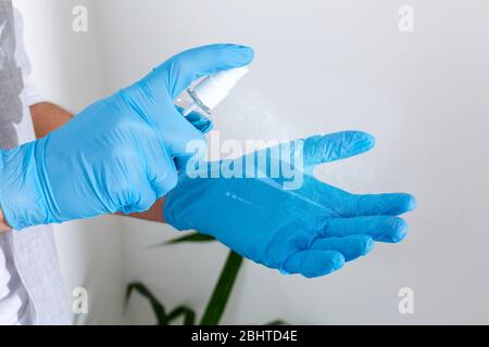 Hand in Gummi-OP-Handschuhe halten antiseptische Hand Desinfektionsmittel auf Hintergrund. Alkohol Desinfektionsmittel oder Gel für die Handhygiene Corona Virenschutz Stockfoto