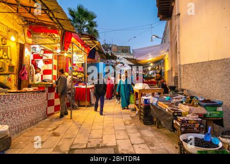 Eine schmale Straße mit Marktständen und Geschäften in den Souks in der Medina, Fes, Marokko Stockfoto