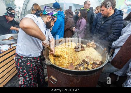 Samara, Russland - 5. Oktober 2019: Kochen appetitlich traditionellen orientalischen Pilaf in einem großen Kessel im Freien während der ethnischen Urlaub Stockfoto