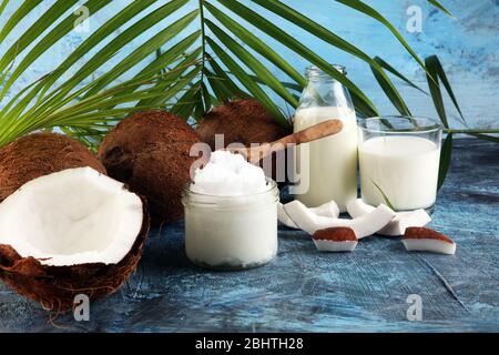 Kokosöl mit frischen Nüssen und Palmblättern auf dem Hintergrund. Reife Kokosnussfrüchte Stockfoto