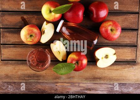 Apfelmost-Getränk und Äpfel mit Blättern auf rustikalem Tisch Stockfoto