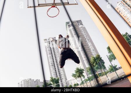 Outdoor-Aktivitäten. African Mann Basketball spielen auf dem Platz Springen machen Schuss schreien motiviert Stockfoto