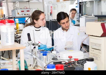 Zwei Studierende der Fakultät für Chemie der Universität Experimente im Labor, die Ergebnisse in der Arbeitsmappe Stockfoto