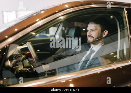 Porträt von selbstbewussten bärtigen Geschäftsmann trägt Business-Anzug sitzt hinter dem Lenkrad des neuen Autos Stockfoto