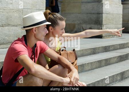 Das junge Paar im Urlaub saß auf einer Treppe, die in die Ferne zeigte Stockfoto