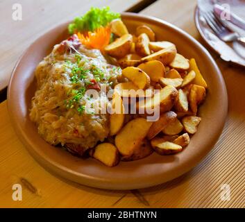 Traditionelles polnisches Eintopf mit Schweinefleisch und Sauerkraut mit Beilage aus gebackenen Kartoffeln Stockfoto