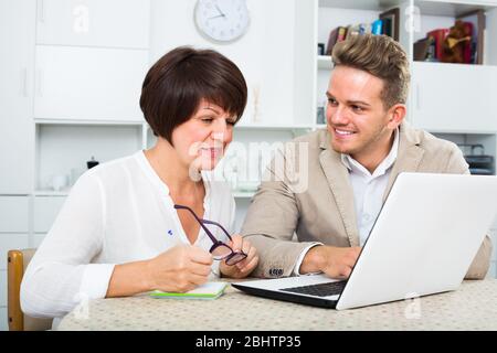 Lächelnde Mutter und Sohn neue Software auf dem Laptop am Tisch sitzen berücksichtigen Stockfoto