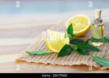 Flasche mit Minzöl, Zitrone und frischen grünen Minzblättern auf Holzhintergrund. Selektiver Fokus. Stockfoto