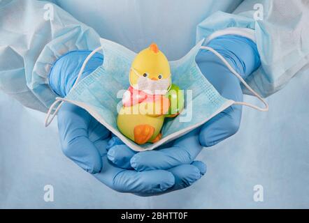 Medics Hände in Schutzhandschuhen halten ein Teddyhähnchen in einer medizinischen Maske. Quarantäne Kinderschutz. Stoppen Sie das Coronavirus-Konzept. Selbstisolierung, SoC Stockfoto