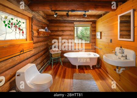 Ein Badezimmer in einem rustikalen Berghütte mit Waschbecken, Toilette und Badewanne mit Clawfoot. Stockfoto