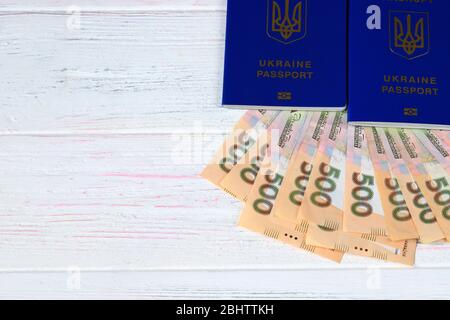Ukrainische ausländische biometrische Pass mit der Inschrift in Ukrainisch - Ukraine Pass mit Griwna Notizen auf einem weißen Holzhintergrund. Das Konzept Stockfoto