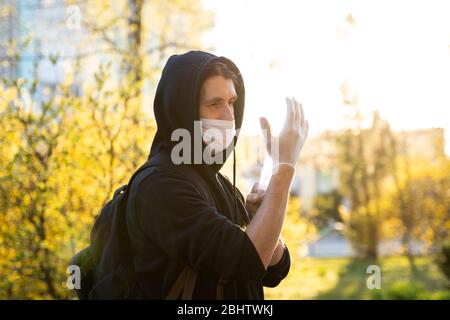 Mann in schwarzem Hoodie in einer medizinischen Maske mit Gummihandschuhen, um Keime, giftige Dämpfe, Staub zu verhindern. Prävention von bakteriellen Infektion Coronavirus oder Stockfoto