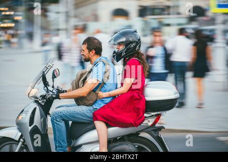 MOSKAU - RUSSLAND 02. JULI 2017: Ein junger kaukasischer Mann fährt ein Mädchen auf einem Motorrad. Das Mädchen ist in einem roten Kleid gekleidet, der Mann in Jeans Stockfoto