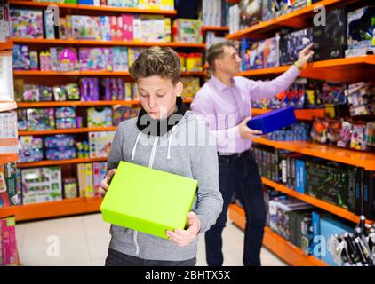 Teen junge suchen eng an Karton mit neuen Spielzeug in Kinder Spielzeug-Shop Stockfoto