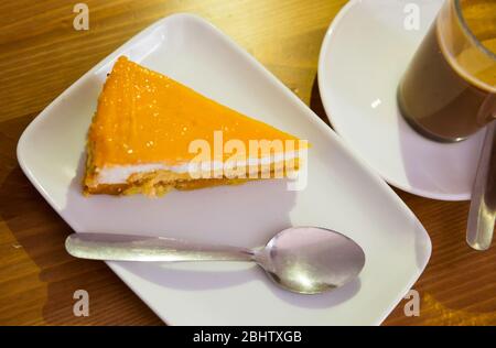 Scheibe KarottenBiskuitkuchen mit leichter Quark-Creme und Pfirsichglasur in Nusskrume Stockfoto