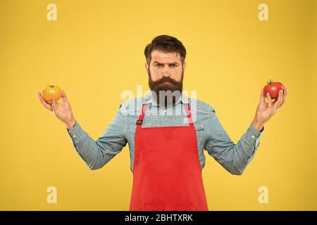 Essen Sie mehr Tomaten. Vorteilhaft für die Gesundheit der Haut. Gesundheitliche Vorteile der Tomate. Saftiges und süßes Gemüse. Brutales Kochen in der Schürze. Bärtiger Koch mit Tomaten. Ernährung schützen Sie sich vor Krebs. Stockfoto