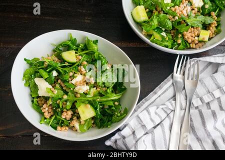 Zitronen-Arugula-Salat mit Couscous, Gurken und Feta: Rucula-Salat mit Gurkenstückchen, Feta-Käsebröseln und Vollkorn-Perlmutt-Couscous Stockfoto