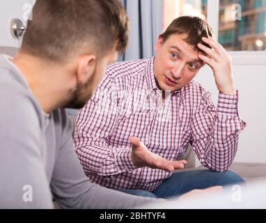 Gestörte Mensch, ernstes Gespräch mit seinem Freund auf dem Sofa zu Hause Stockfoto