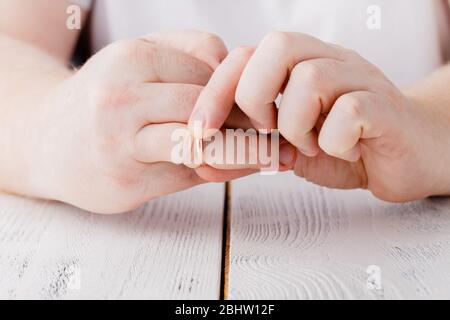 Mann entfernt einen goldenen Ehering von seinem Finger. Konzept der Familie Streit, Scheidung oder Verrat Stockfoto