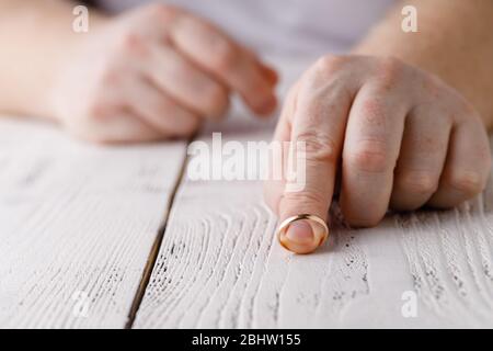 Mann entfernt einen goldenen Ehering von seinem Finger. Konzept der Familie Streit, Scheidung oder Verrat Stockfoto