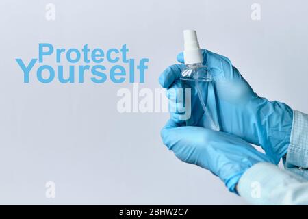 Der Arzt in medizinischen Handschuhen hält ein Antiseptikum und neben der Inschrift schützen Sie sich. Nahaufnahme. Stockfoto