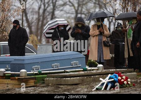 Boston, Massachusetts, USA. April 2020. Der COVID-19, Corona Virus, in Massachusetts ist der drittam schlimmsten getroffenen Staat in Amerika. Eine Familie begräbt am Montag, den 27. April 2020, zwei Verwandte im Calvary Cemetary im Dorchester-Viertel von Boston im Regen. Kredit: Allison Dinner/ZUMA Wire/Alamy Live News Stockfoto