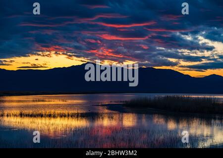 Das Nachleuchten der untergehenden Sonne spiegelt sich auf den Wolken und dem Wasser des Bear River Zugvogelschutzgebiets in der Nähe von Brigham City, Box Elder County, Utah. Stockfoto