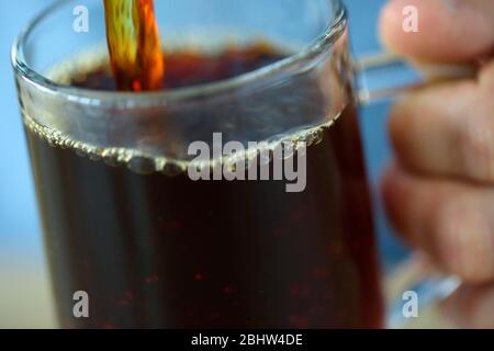 Heißer schwarzer Kaffee, der in ein Glas gegossen wird Stockfoto