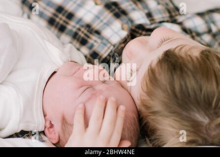 Großer Bruder und neugeborenes Baby Schwester kuscheln auf dem Bett Stockfoto