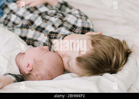 Großer Bruder und neugeborenes Baby Schwester kuscheln auf dem Bett Stockfoto