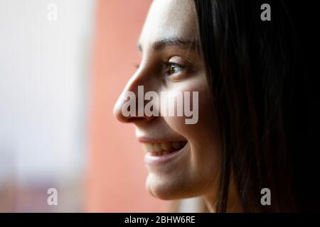 Frau, die an einem regnerischen Tag aus dem Fenster schaut. Konzept des Ausblickens aus dem Fenster. Stockfoto