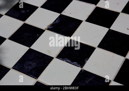 Closeup of a board of black and white tiles that are worn by inclement weather Stockfoto