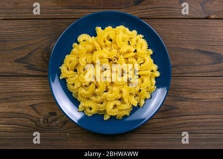 Pene Lisce Pasta in blauer Platte auf dunklem Holzhintergrund. Von oben Stockfoto